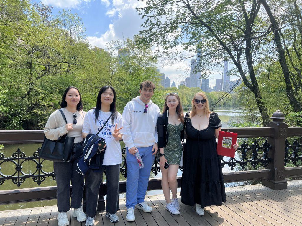 一群2024年春季的学生在中央公园的桥前的水