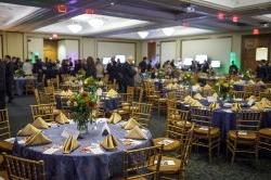 在会议中心主宴会厅举行的2012年晚宴上，紫色的桌布和金色的餐巾装饰.