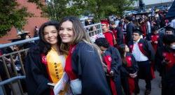 Students wearing regalia smiling together at Commencement