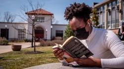 Photo of student reading a book on campus