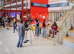 SCM students filming on lobby stairs