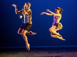 Two dancers on stage jumping in mid-air