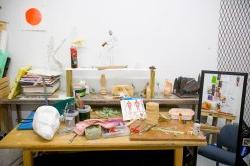 Photo of MFA studio workspace with lots of art supplies on table.